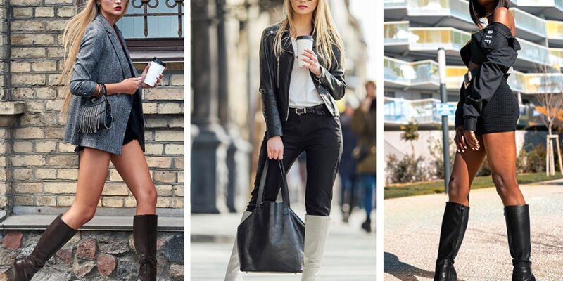 Stylish woman in a gray blazer, black shorts, and knee-high boots walks past a brick wall, holding a coffee.