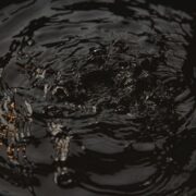 Close-up of dark water surface with ripples and droplets creating circular waves at night.