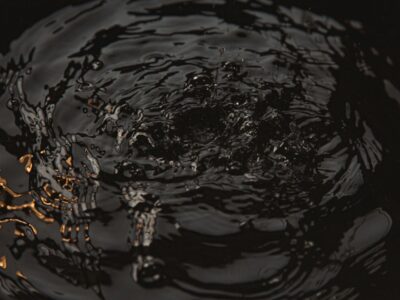Close-up of dark water surface with ripples and droplets creating circular waves at night.